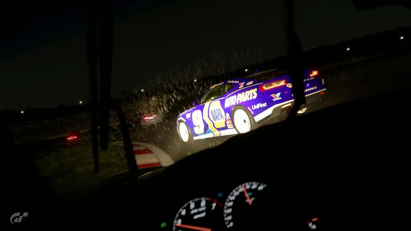 Cockpit view at night in the rain, chasing a blue number 9 race car through a corner